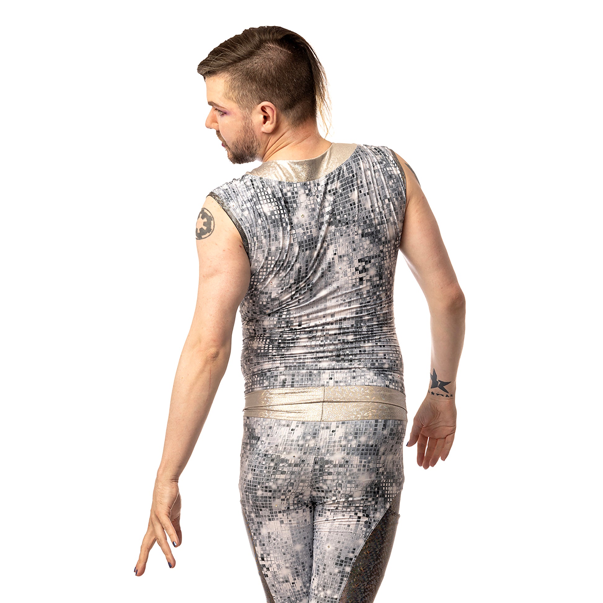 Disco Diva Leggings, a handmade-to-order piece in disco ball and silver foil print spandex. The leggings feature a double layer high waist with light silver knee panels and granite foil curved leg panels. Model Max stands with their back to the camera looking slightly over their shoulder. 