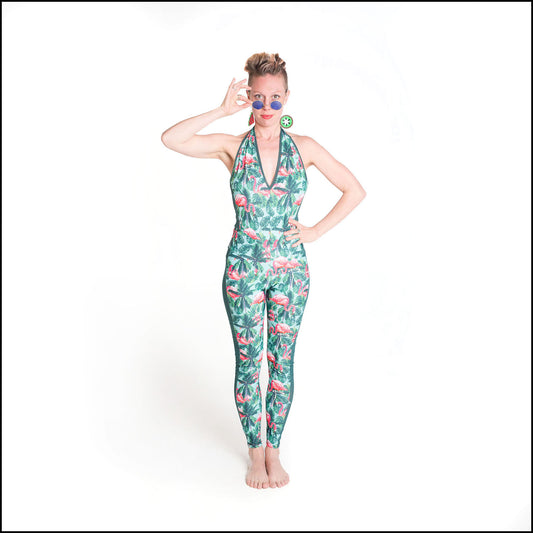 Tropicana Catsuit, a handmade-to-order piece in flamingo and palm printed spandex. This backless catsuit is both stylish and sustainable. The halter neck design features a flattering V-neck with green mesh trim and full length mesh side panels.
