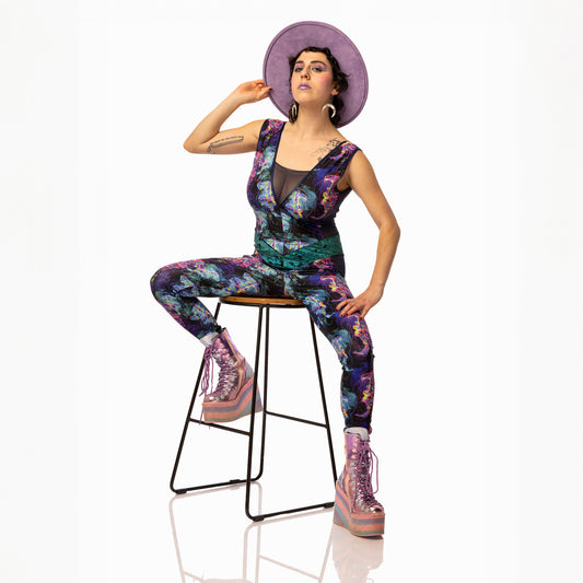 Jellyfish Catsuit, a handmade-to-order piece in purple, black, pink and green tropical jellyfish  printed spandex. This low back catsuit is both stylish and sustainable. The v-neck design features a flattering teal, foiled velvet waist panel and black mesh front insert and side panels.