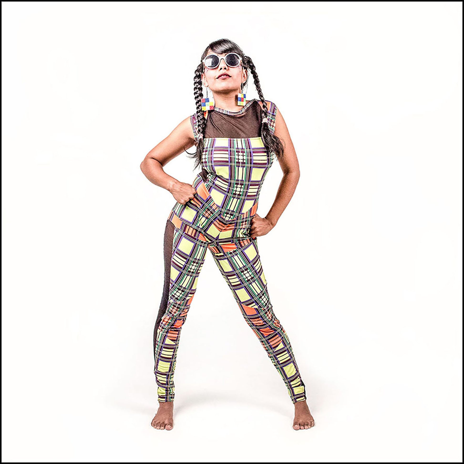 Neon Tartan Catsuit, a handmade-to-order piece in yellow and orange neon tartan printed spandex. This statement catsuit is both stylish and sustainable. The reversible design features a square mesh front neck and v-shaped back neck (for the style reversed see the Mardi Gras Catsuit). It includes black mesh side panels and multiple contrast panels. 