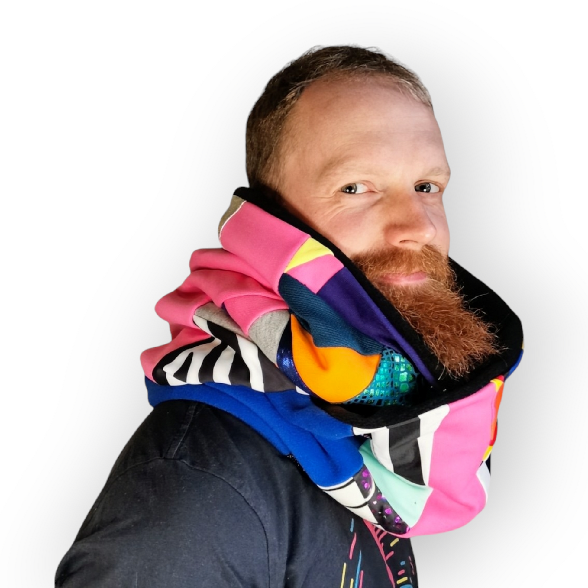Large circular scarf made from recycled scrap fabrics.  Lined in black fleece and including bright, printed, multi coloured patchwork panels and large colour blocks in grey, pink, purple and blue. Pictured on model wrapped twice  around neck. 