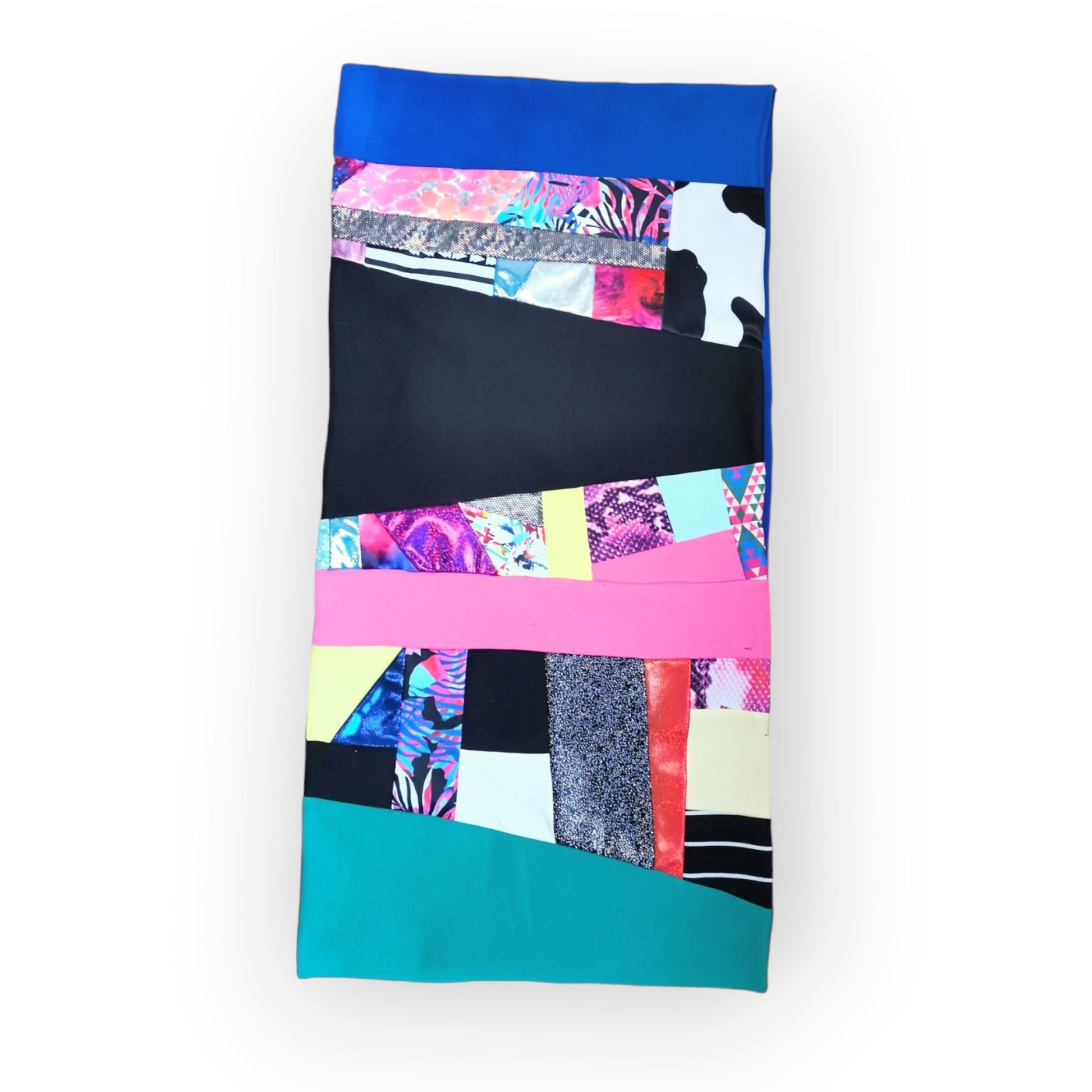 Large circular scarf made from recycled scrap fabrics.  Lined in blue fleece and including bright, printed, multi coloured patchwork panels and large colour blocks in turquoise, pink, black and blue. Pictured flat on white background. 