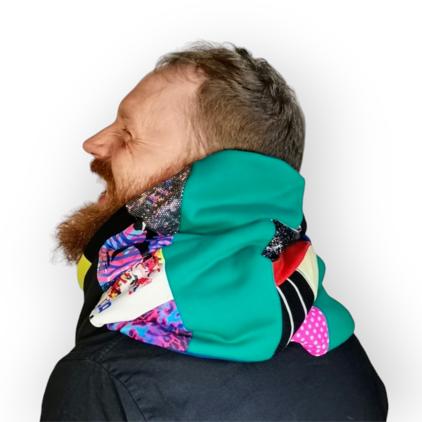 Large circular scarf made from recycled scrap fabrics.  Lined in blue fleece and including bright, printed, multi coloured patchwork panels and large colour blocks in turquoise, pink, black and blue. Pictured on a model  wrapped around neck twice. 