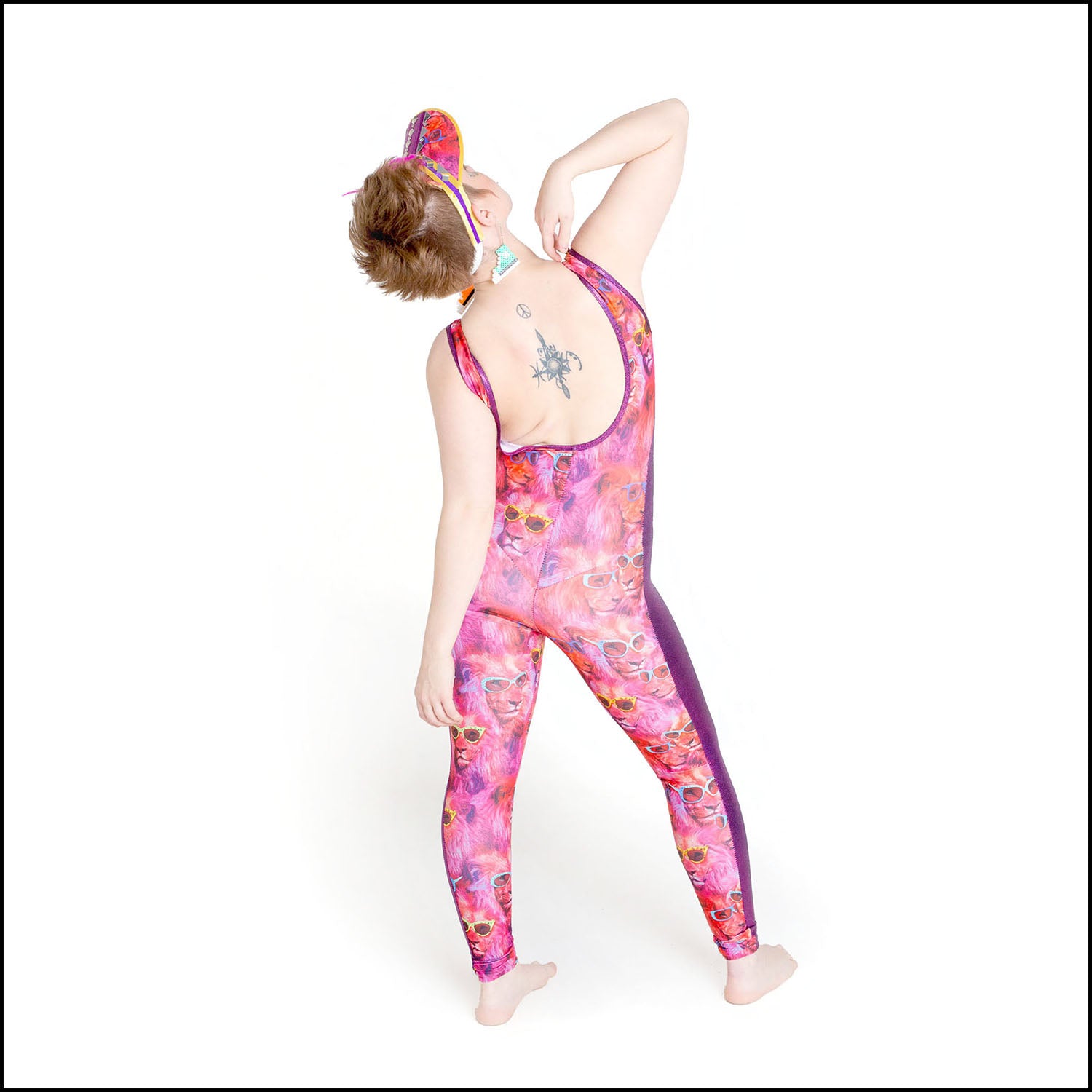 Cool Catsuit, a handmade-to-order piece in lion fest printed spandex. This statement catsuit is both stylish and sustainable. The unisex design features a flattering V-neck with a purple mesh insert and pink hologram foil full length side panels.
